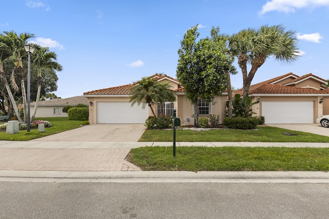 7117 Treviso Ln, Boynton Beach, FL 33472 - mediterranean / spanish home with an attached garage, stucco siding, a tile roof, a front lawn, and driveway