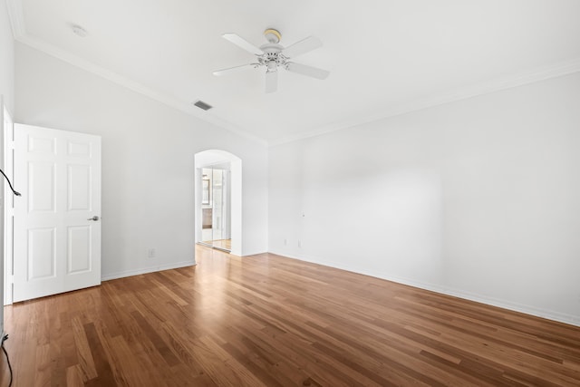 empty room with arched walkways, visible vents, ornamental molding, and wood finished floors