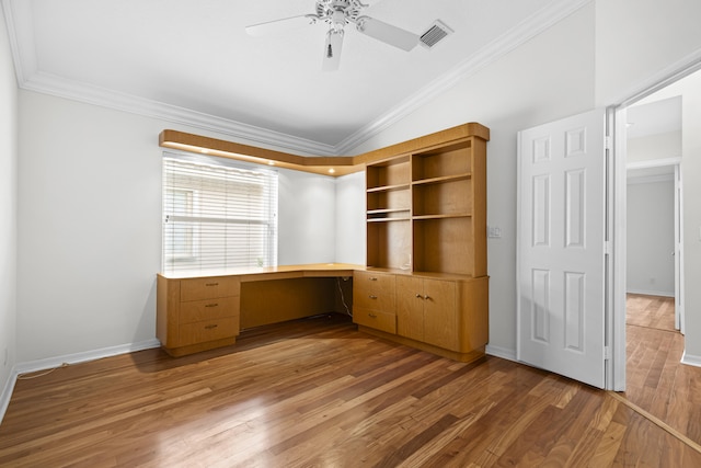 unfurnished office featuring visible vents, ornamental molding, wood finished floors, vaulted ceiling, and built in study area