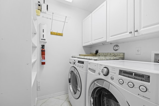 washroom featuring light tile patterned floors, baseboards, cabinet space, and washer and clothes dryer