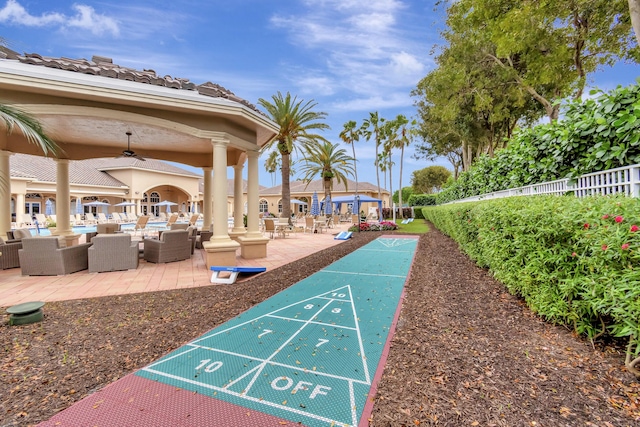 view of home's community featuring a patio area, shuffleboard, and fence