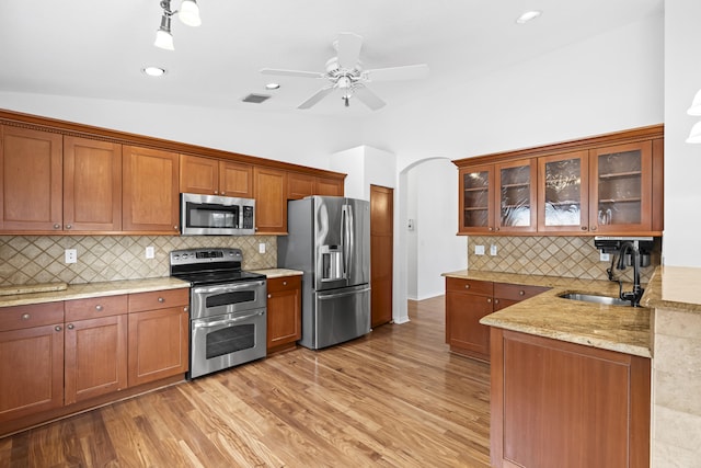 kitchen featuring light wood-style floors, brown cabinets, appliances with stainless steel finishes, and a sink