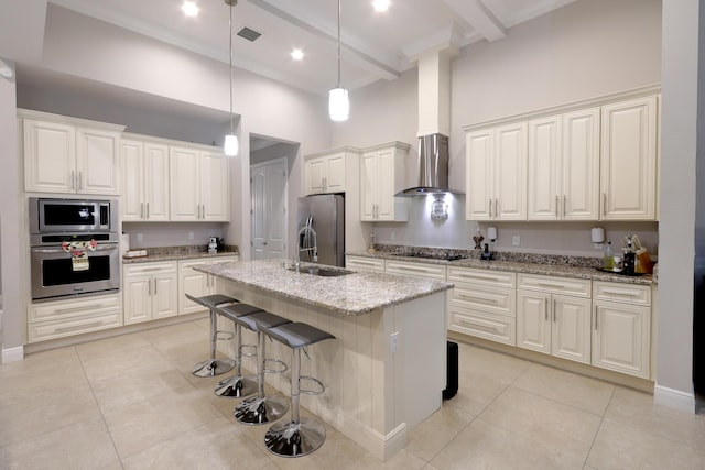 kitchen with light tile patterned floors, appliances with stainless steel finishes, wall chimney exhaust hood, and a high ceiling