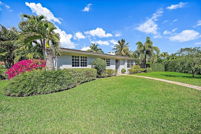 ranch-style home featuring brick siding and a front lawn