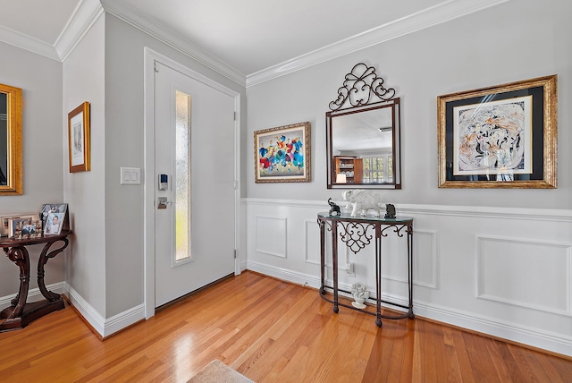 entrance foyer featuring a decorative wall, wainscoting, light wood-type flooring, and crown molding