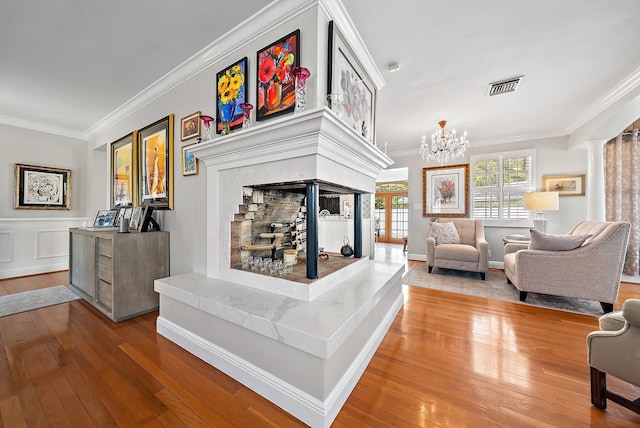 living area featuring visible vents, crown molding, ornate columns, and hardwood / wood-style floors