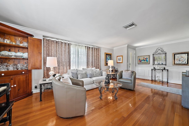 living room with visible vents, crown molding, and light wood-type flooring