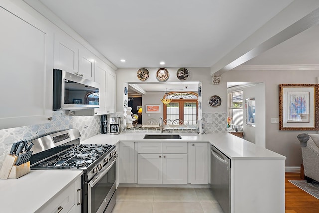 kitchen with a sink, stainless steel appliances, a peninsula, and light countertops