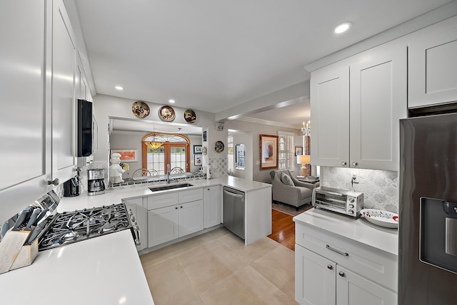 kitchen featuring ornamental molding, a sink, open floor plan, stainless steel appliances, and decorative backsplash