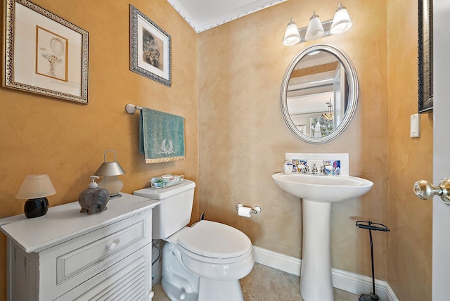 half bath with tile patterned flooring, toilet, baseboards, and a sink