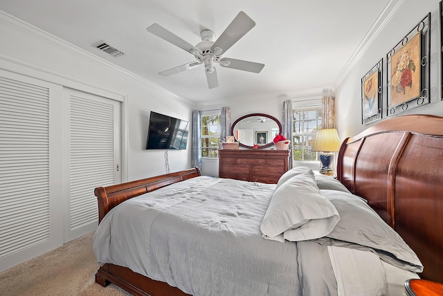 carpeted bedroom with visible vents, a closet, ornamental molding, and a ceiling fan