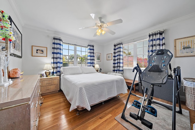 bedroom featuring a ceiling fan, light wood-style floors, and ornamental molding