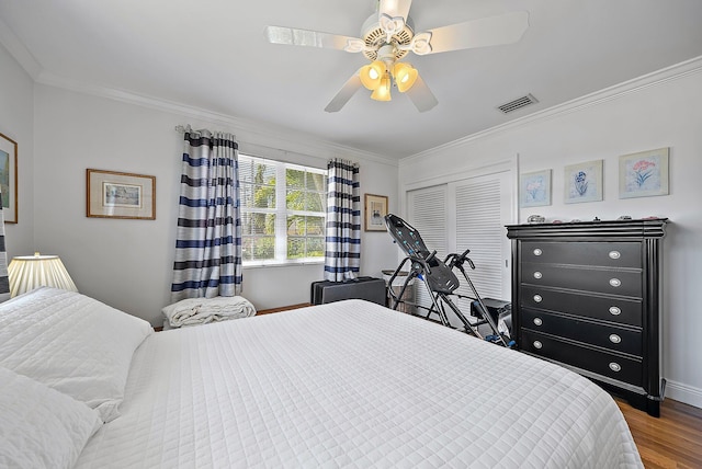 bedroom with visible vents, ornamental molding, a ceiling fan, wood finished floors, and a closet