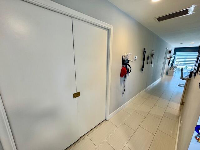 hall featuring light tile patterned flooring and visible vents