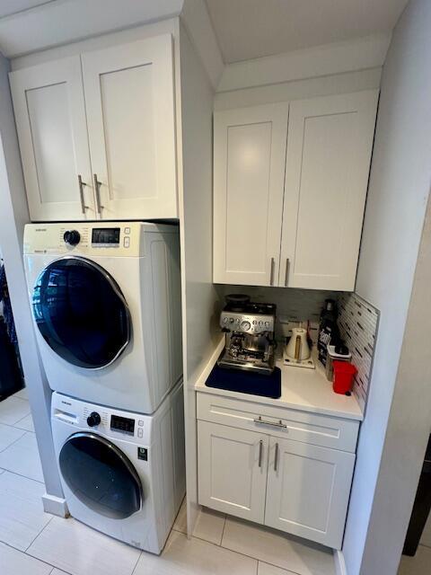 clothes washing area featuring stacked washer and clothes dryer and light tile patterned flooring