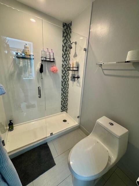 bathroom featuring toilet, a stall shower, and tile patterned flooring