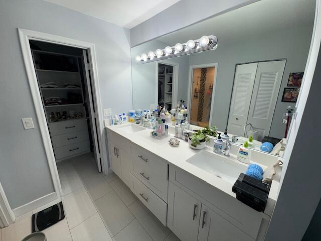 full bathroom with a walk in closet, double vanity, tile patterned floors, and a sink