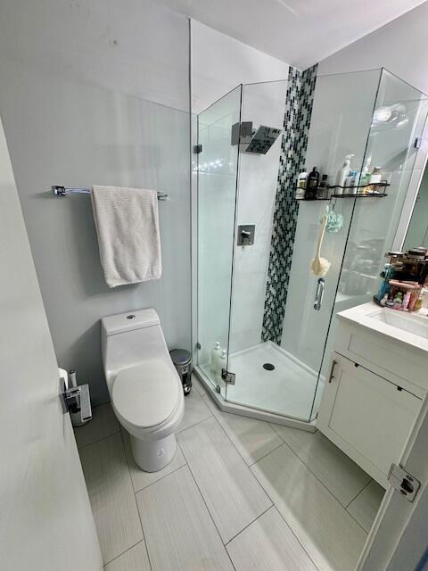 full bathroom featuring a stall shower, toilet, and vanity