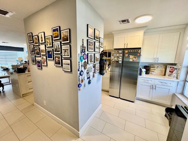 hallway with light tile patterned flooring, visible vents, and baseboards