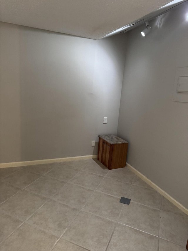 spare room with baseboards and light tile patterned floors