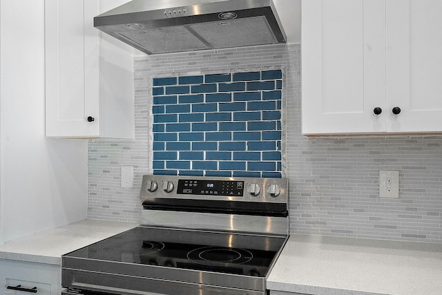 kitchen with backsplash, white cabinets, stainless steel electric range oven, and wall chimney range hood