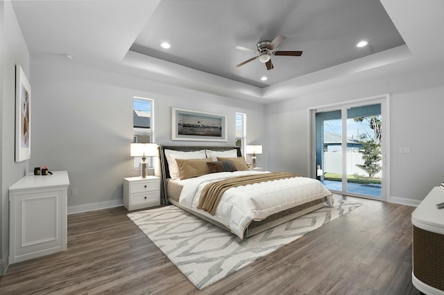 bedroom featuring access to exterior, dark wood finished floors, and a tray ceiling