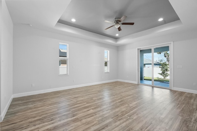 unfurnished room with baseboards, a raised ceiling, and wood finished floors