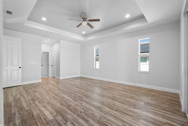 empty room featuring a wealth of natural light, visible vents, and a raised ceiling