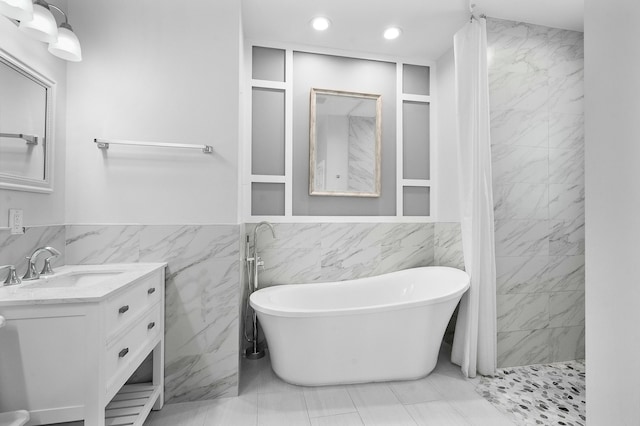 bathroom with vanity, recessed lighting, a shower with curtain, a freestanding tub, and tile walls