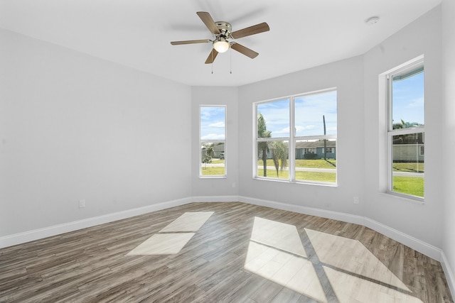 unfurnished room featuring a ceiling fan, baseboards, and wood finished floors