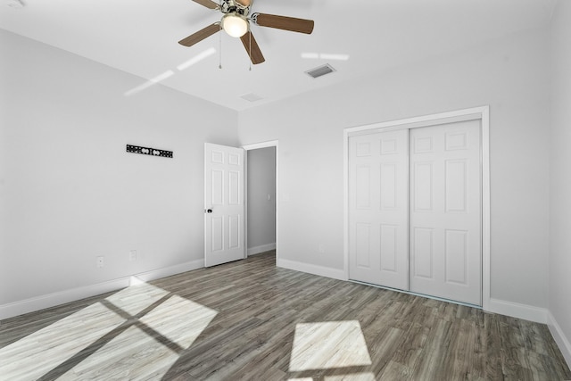 unfurnished bedroom featuring a closet, visible vents, baseboards, and wood finished floors