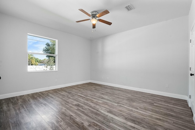 empty room featuring ceiling fan, visible vents, baseboards, and dark wood-style floors