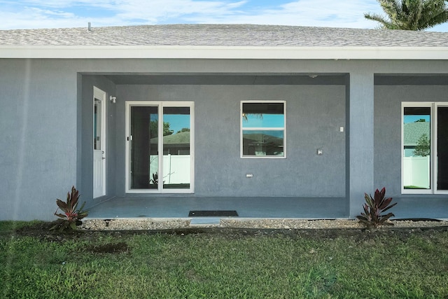 rear view of house with roof with shingles and stucco siding