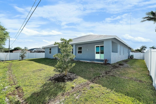 back of property featuring a fenced backyard, a lawn, and stucco siding