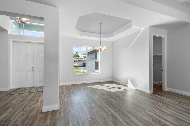 foyer featuring an inviting chandelier, wood finished floors, and a raised ceiling