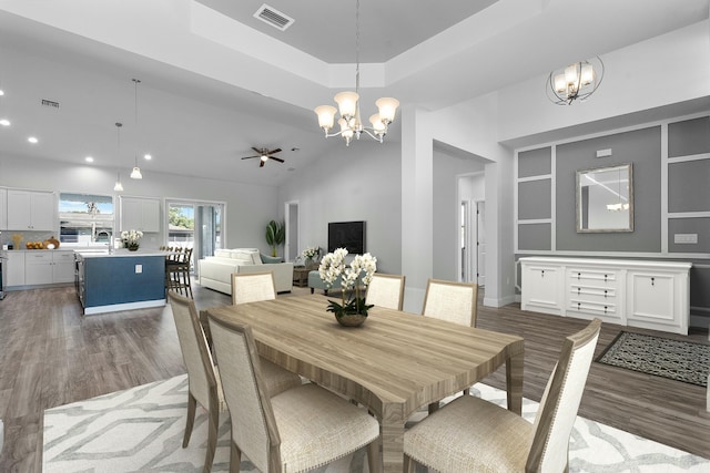 dining room featuring dark wood finished floors, visible vents, a raised ceiling, and lofted ceiling