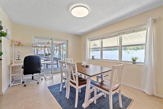 dining area with light tile patterned flooring, baseboards, and a textured ceiling