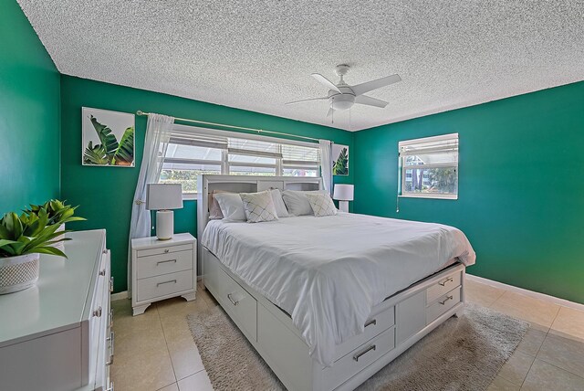 bedroom with light tile patterned floors, baseboards, a textured ceiling, and a ceiling fan