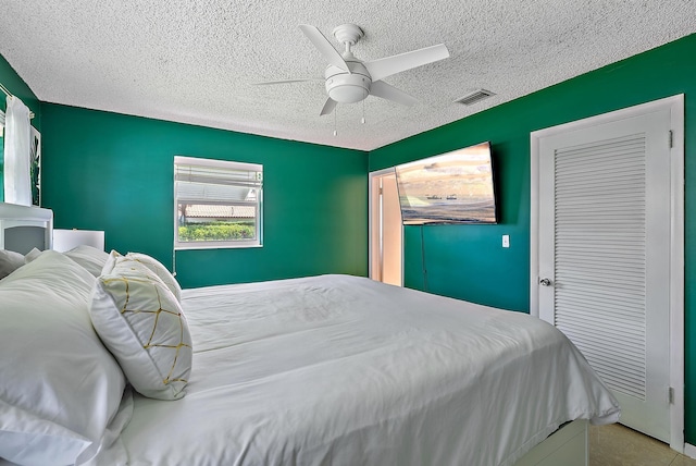 bedroom featuring ceiling fan, visible vents, and a textured ceiling