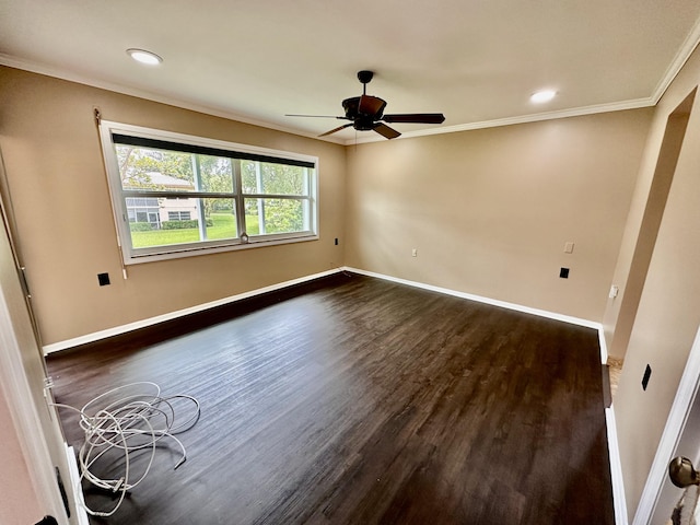 spare room featuring dark wood-type flooring, crown molding, baseboards, and ceiling fan