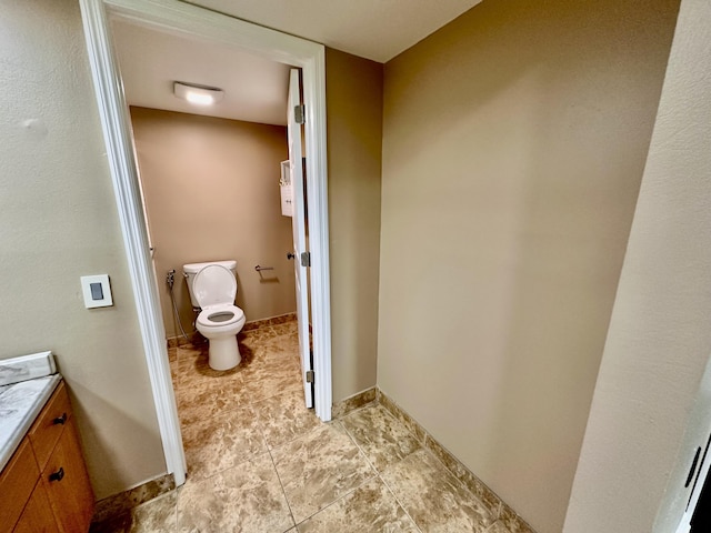 bathroom with baseboards, toilet, and vanity