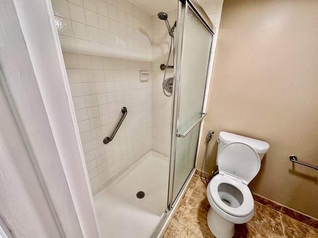 bathroom with a shower stall, toilet, and baseboards