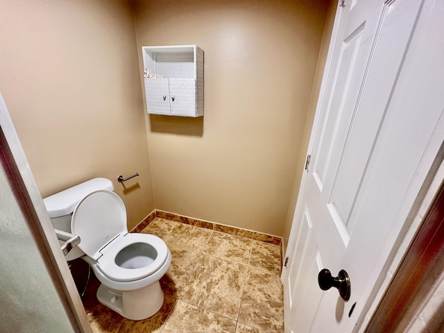 bathroom featuring baseboards, toilet, and tile patterned flooring