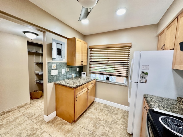 kitchen with freestanding refrigerator, light tile patterned flooring, baseboards, and backsplash