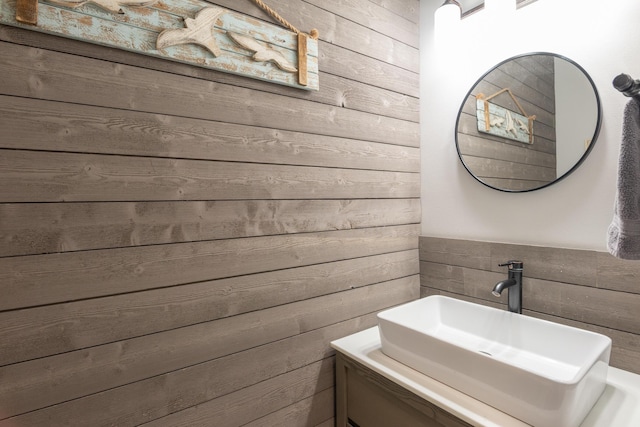 bathroom featuring a sink and wood walls