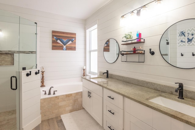 full bath featuring a sink, a stall shower, a bath, and double vanity