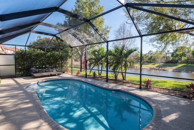 outdoor pool with glass enclosure, a patio, and a water view