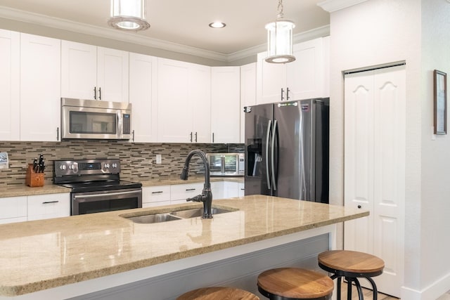 kitchen with tasteful backsplash, ornamental molding, white cabinets, stainless steel appliances, and a sink