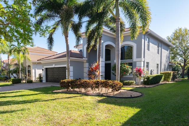 mediterranean / spanish-style house with stucco siding, driveway, a front yard, and an attached garage