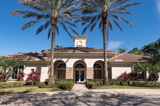 view of front of home with a tiled roof, french doors, and stucco siding